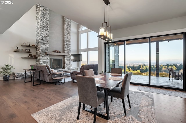 dining room with hardwood / wood-style flooring and a stone fireplace