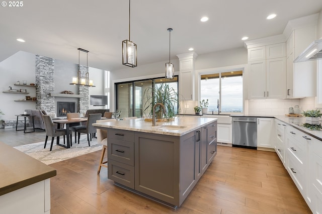 kitchen featuring wall chimney range hood, decorative backsplash, a sink, and gray cabinetry