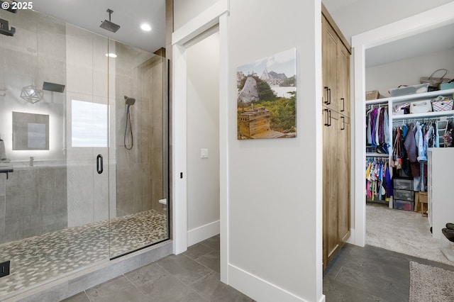 bathroom featuring a shower stall, baseboards, and a walk in closet
