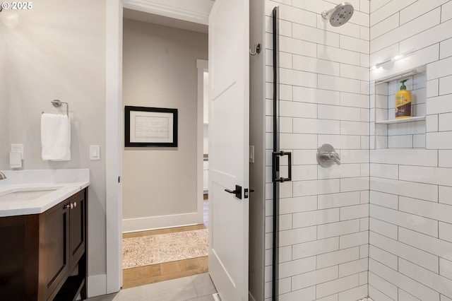 bathroom with baseboards, vanity, wood finished floors, and a stall shower