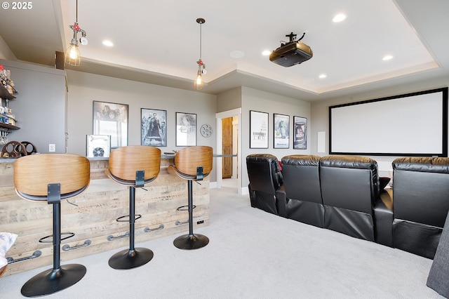 home theater room with a raised ceiling and light colored carpet