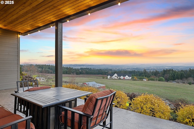 patio terrace at dusk featuring a lawn