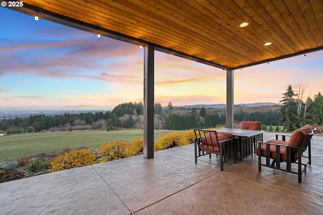 patio terrace at dusk featuring a yard