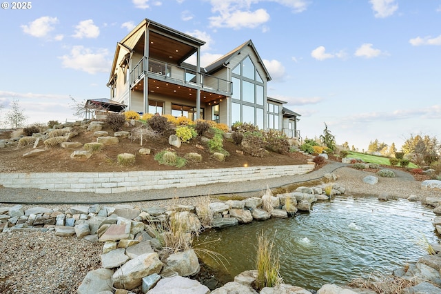 rear view of house with a balcony and a small pond
