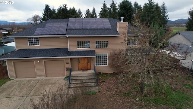 view of front of house featuring a mountain view, a garage, and solar panels