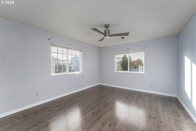 empty room with dark hardwood / wood-style floors, a wealth of natural light, and ceiling fan