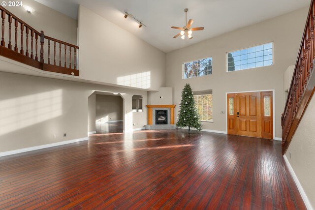 unfurnished living room with hardwood / wood-style flooring, ceiling fan, and a high ceiling