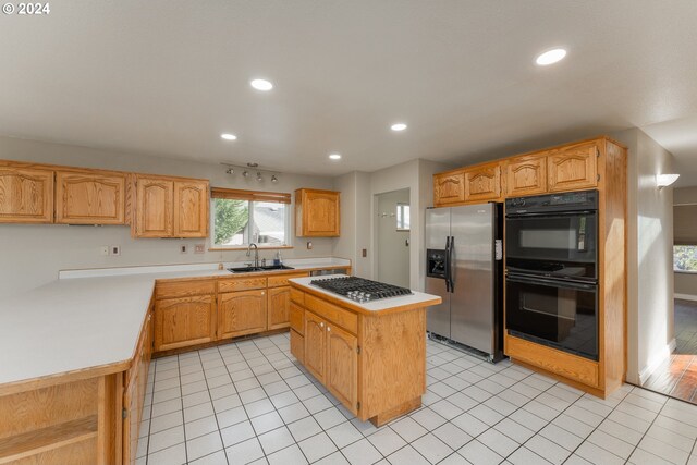 kitchen featuring appliances with stainless steel finishes, a center island, sink, and light tile patterned floors