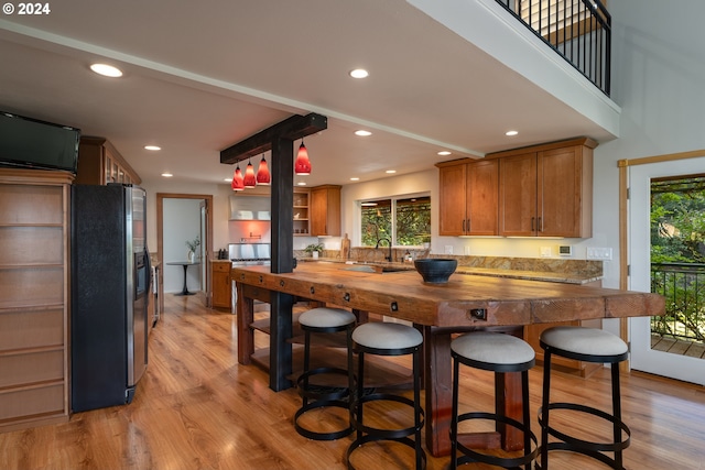 kitchen with a healthy amount of sunlight, butcher block counters, sink, and stainless steel fridge with ice dispenser