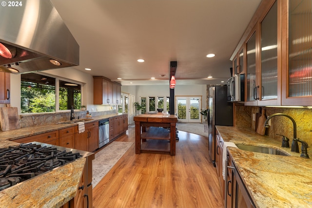 kitchen featuring light stone countertops, island exhaust hood, sink, and appliances with stainless steel finishes