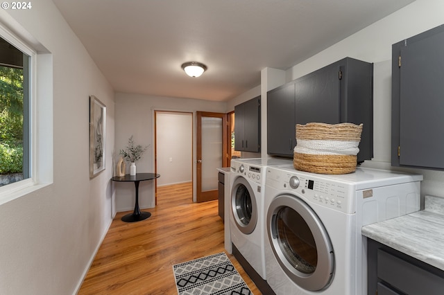 clothes washing area with cabinets, washer and dryer, and light wood-type flooring