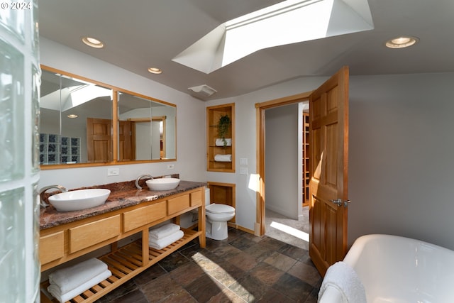 bathroom with vanity, a skylight, toilet, and a bathing tub