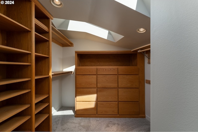 spacious closet featuring light colored carpet and vaulted ceiling with skylight