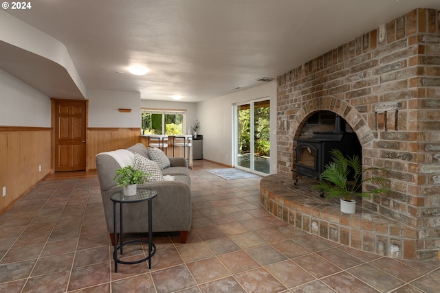 tiled living room featuring wooden walls and a wood stove