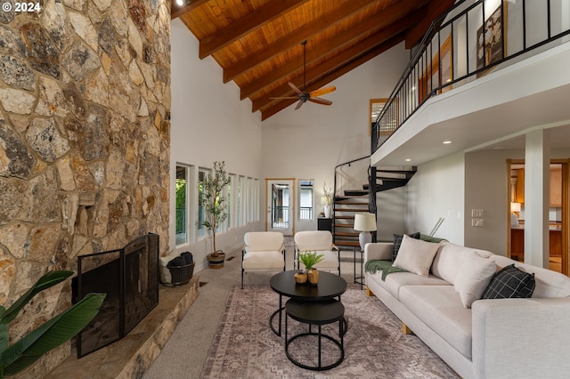 carpeted living room featuring vaulted ceiling with beams, ceiling fan, a fireplace, and wooden ceiling