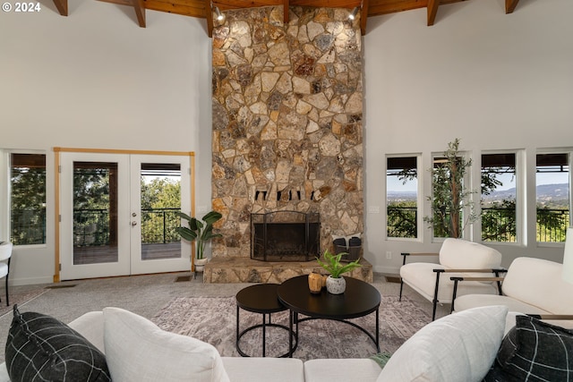 living room featuring a stone fireplace, french doors, beamed ceiling, and a towering ceiling