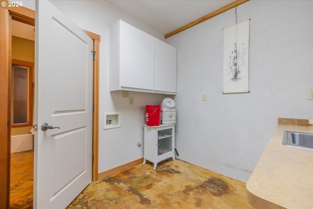 clothes washing area featuring hookup for a washing machine, crown molding, and cabinets