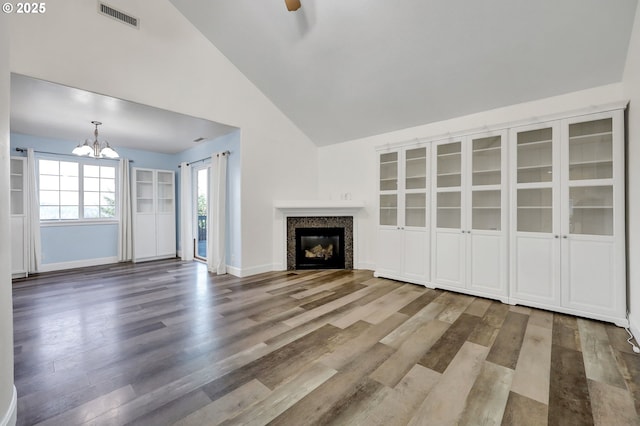 unfurnished living room with wood-type flooring, ceiling fan with notable chandelier, and high vaulted ceiling