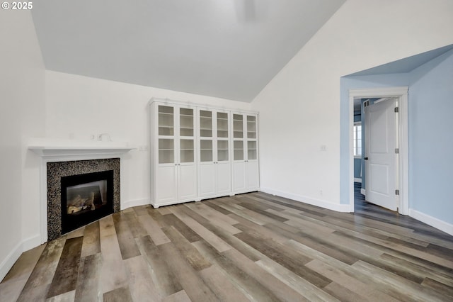 unfurnished living room featuring high vaulted ceiling and wood-type flooring