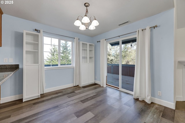 unfurnished dining area with a chandelier and dark wood-type flooring