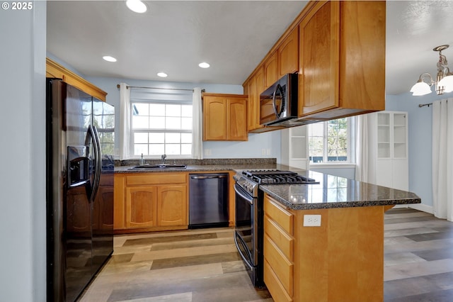 kitchen featuring sink, stainless steel appliances, dark stone counters, and light hardwood / wood-style floors