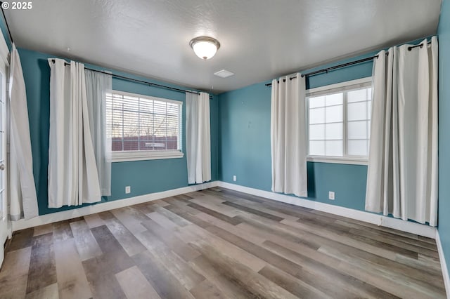 unfurnished room featuring wood-type flooring and a textured ceiling