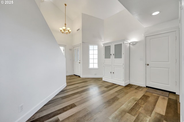 entryway with wood-type flooring and an inviting chandelier