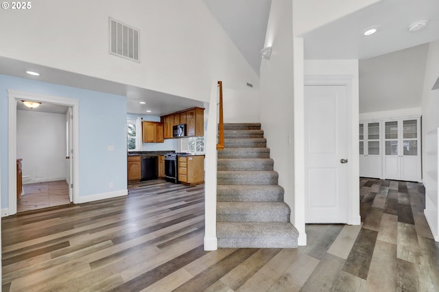 stairway featuring hardwood / wood-style flooring and high vaulted ceiling