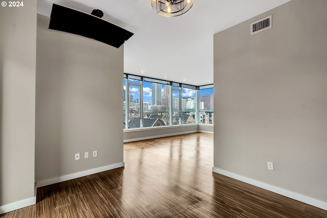 empty room with a notable chandelier and dark wood-type flooring