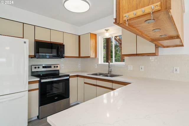 kitchen featuring backsplash, white refrigerator, sink, stainless steel electric range oven, and kitchen peninsula