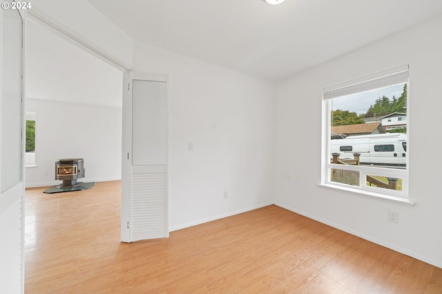 spare room featuring hardwood / wood-style floors, a wood stove, and a wealth of natural light