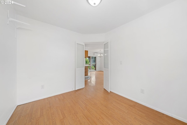 unfurnished room featuring light hardwood / wood-style floors and a notable chandelier