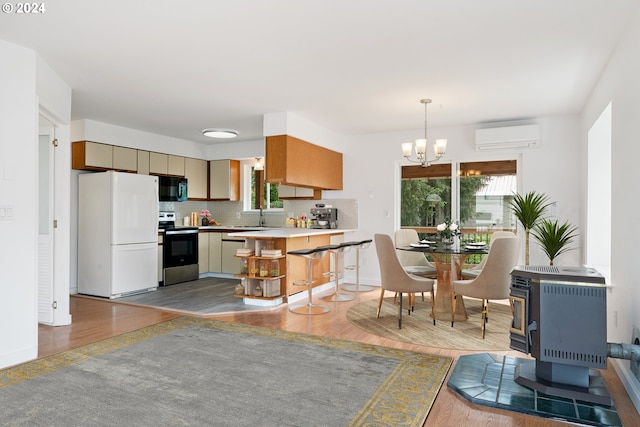 kitchen featuring a wood stove, white refrigerator, electric stove, a wall mounted AC, and light hardwood / wood-style floors