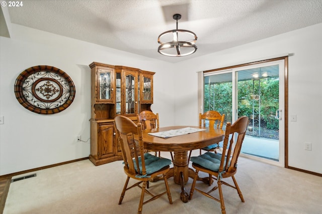 carpeted dining room featuring a textured ceiling and a notable chandelier