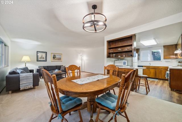 dining area with a chandelier, sink, light hardwood / wood-style floors, and a textured ceiling