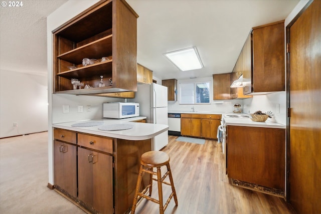 kitchen featuring sink, ventilation hood, light hardwood / wood-style floors, white appliances, and a breakfast bar area