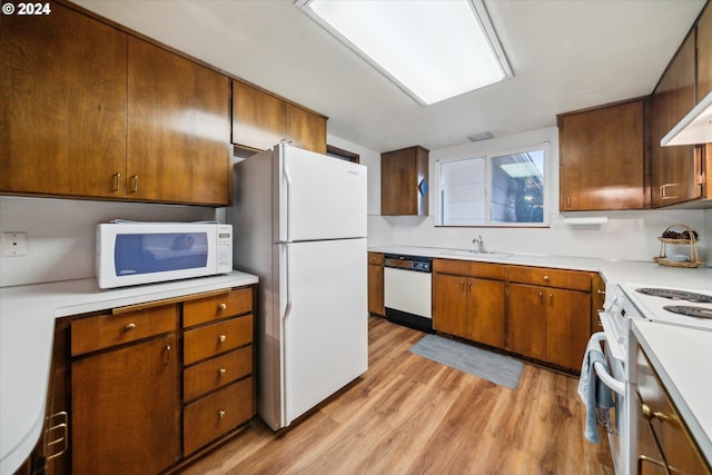 kitchen with white appliances, sink, and light hardwood / wood-style floors