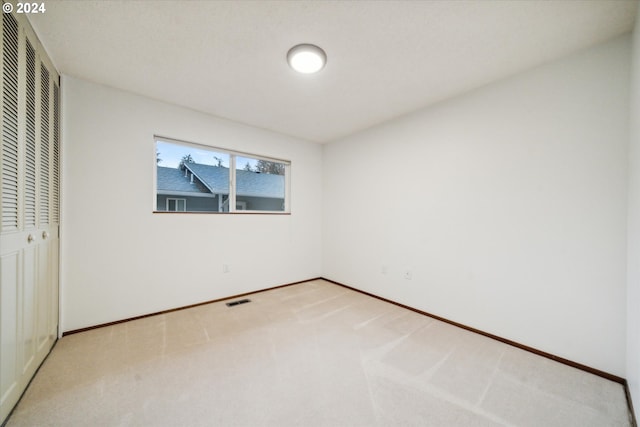 unfurnished bedroom featuring a closet and light colored carpet