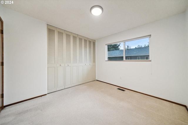 unfurnished bedroom with light carpet and a closet