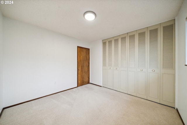 unfurnished bedroom with a closet and light colored carpet