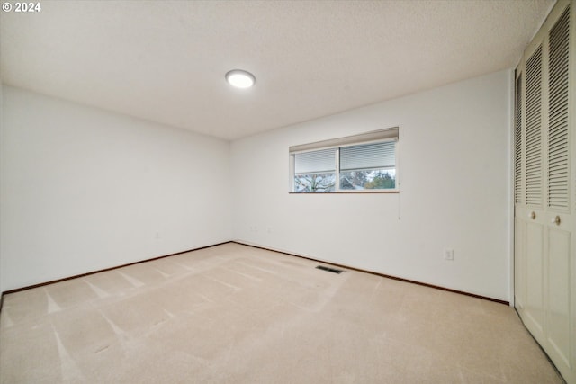 unfurnished bedroom with a closet, light colored carpet, and a textured ceiling