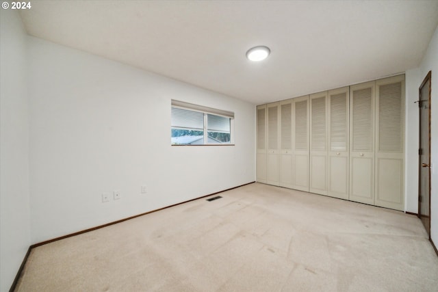 unfurnished bedroom featuring light carpet and a closet