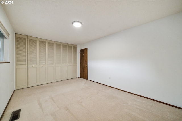 unfurnished bedroom featuring a closet and light carpet