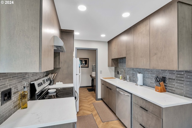 kitchen with tasteful backsplash, sink, wall chimney range hood, light parquet floors, and stainless steel dishwasher