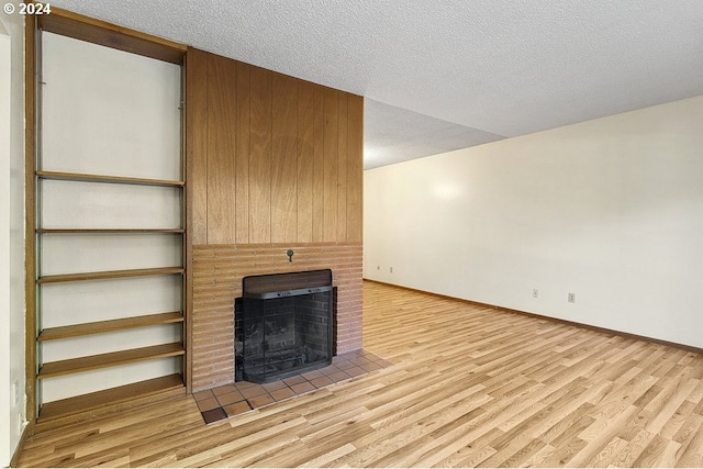 unfurnished living room with light hardwood / wood-style flooring and a textured ceiling