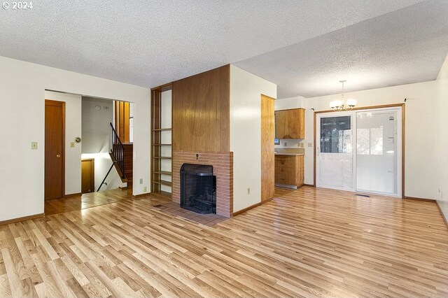 unfurnished living room featuring light wood-type flooring, a fireplace, and a textured ceiling