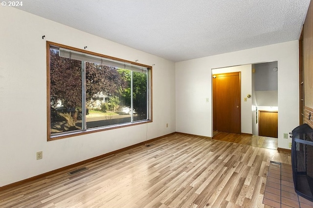 unfurnished bedroom with light wood-type flooring, a textured ceiling, and a closet