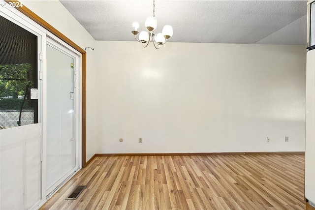 spare room with light hardwood / wood-style flooring, a textured ceiling, and an inviting chandelier