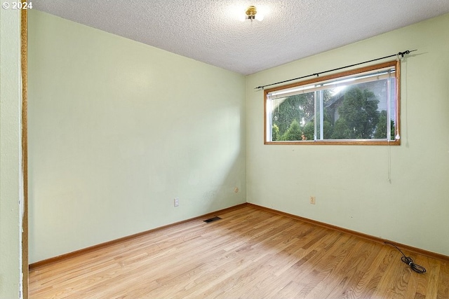 empty room with a textured ceiling and light wood-type flooring