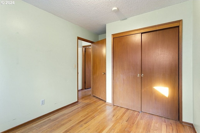 unfurnished bedroom featuring light wood-type flooring, a textured ceiling, and a closet